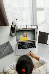 Child participating in an online class with a teacher, using a laptop at home, ideal for educational technology themes.